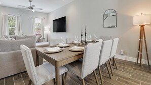 A modern dining room with a wooden table set for four, surrounded by upholstered chairs. - 3BR Downtown SA Home w/ Garage, Walk to Alamodome (San Antonio)