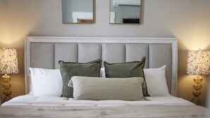 A neatly made bed with a grey upholstered headboard, two wall-mounted mirrors, and two bedside lamps with floral lampshades. - 3BR Downtown SA Home w/ Garage, Walk to Alamodome (San Antonio)