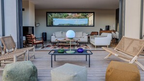 Een moderne woonkamer met een groot televisiescherm, comfortabele zithoek en een houten terras.