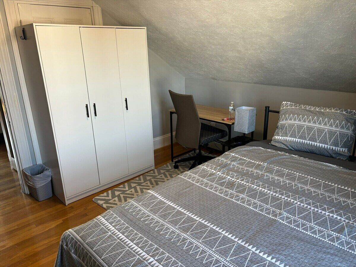 A bedroom with a bed, a desk, a chair, and a wardrobe.