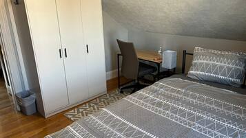 A bedroom with a bed, a desk, a chair, and a wardrobe.