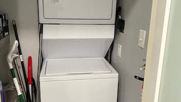 A compact, white Whirlpool washer and dryer unit in a small laundry room with a gray wall.