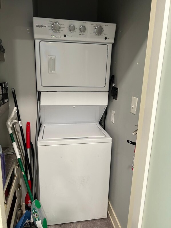 A compact, white Whirlpool washer and dryer unit in a small laundry room with a gray wall. - Homestay Near Downtown Boston (Boston)