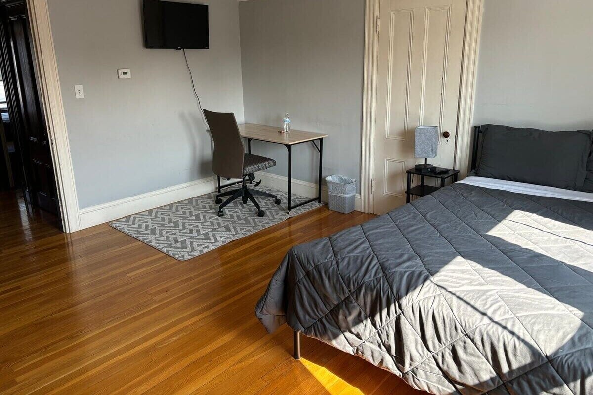 A bedroom with a bed, a desk, and a chair.