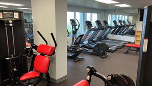 Ein Fitnessstudio mit Trainingsgeräten, Laufbändern und einer Spiegelwand.