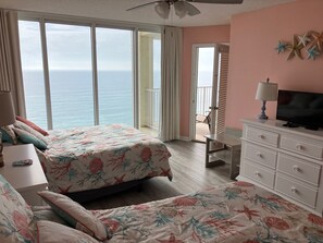 A bedroom with a bed, a sofa, a TV, a dresser, and a balcony with a view of the ocean. - Long Beach Resort 4-1203 2-bedroom condo all new! Easy access & great views. (Panama City Beach)