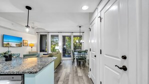 A modern kitchen with a granite countertop, a built-in dishwasher, and a dining area with a table and chairs. - 1 bed/2 bath, walk to Baytowne! Quick tram ride to beach! (Miramar Beach)