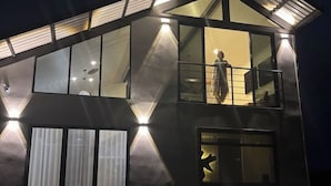 A modern building with a glass facade, multiple balconies, and external lighting.