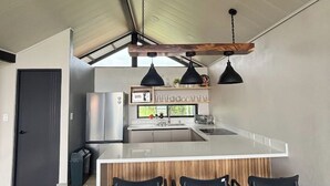 A modern kitchen with a central island, pendant lighting, and a wooden ceiling beam.