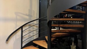A modern spiral staircase with wooden steps and black railings.