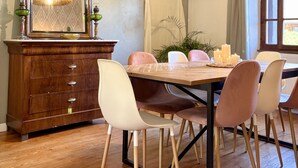 Un comedor con mesa de madera, sillas, un espejo y una lámpara colgante.