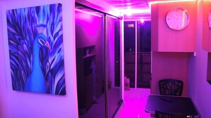 A narrow hallway with a peacock painting, a clock, and a table with chairs. - Modern Oasis - Cozy Loft Condo in Manila (Manila)