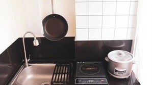A kitchen with a stainless steel sink, a black pan, and a slow cooker. - Modern Oasis - Cozy Loft Condo in Manila (Manila)