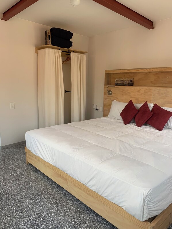 A bedroom with a wooden bed frame, white bedding, and a headboard with a wooden panel. - Chilango BnB (Mexico City)