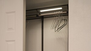 Un placard avec des vêtements suspendus et des bacs de rangement.