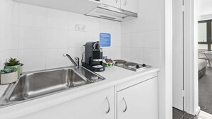 Uma cozinha moderna com pias de aço inoxidável, uma máquina de café e um aviso indicando que as instalações da cozinha são exclusivas para hóspedes.
