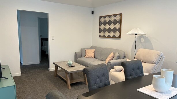 Een moderne woonkamer met een zithoek, een salontafel en een eettafel.