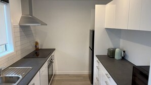 Een moderne keuken met witte kasten, een zwart aanrecht en een roestvrijstalen afzuigkap.