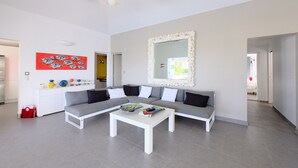 Un salon moderne avec un canapé d’angle gris, une table basse blanche et un grand miroir.
