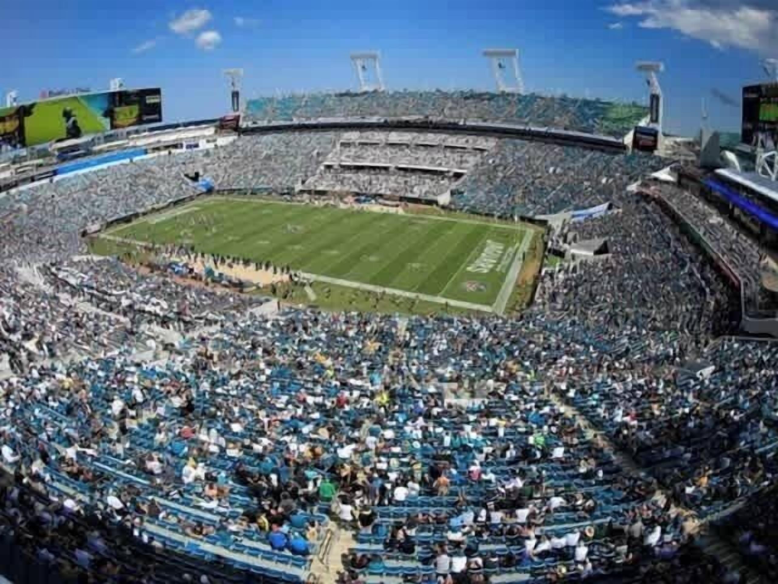 A stadium with multiple tiers of seating, a central field, and a large crowd.