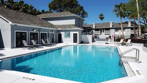 A swimming pool with lounge chairs and a building with a white exterior and grey roof. - 1st Floor, Free PPV, Near Mayo Clinic, Pool, BBQ, (ponte vedra beach)