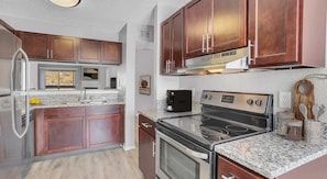 A modern kitchen with dark wood cabinets, stainless steel appliances, and granite countertops.