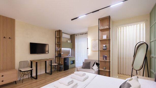 Een moderne hotelkamer met een bed, een bureau, een televisie, een kledingkast en een badkamer.