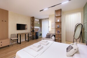 Una habitación de hotel moderna con cama, escritorio, televisor, armario y baño.