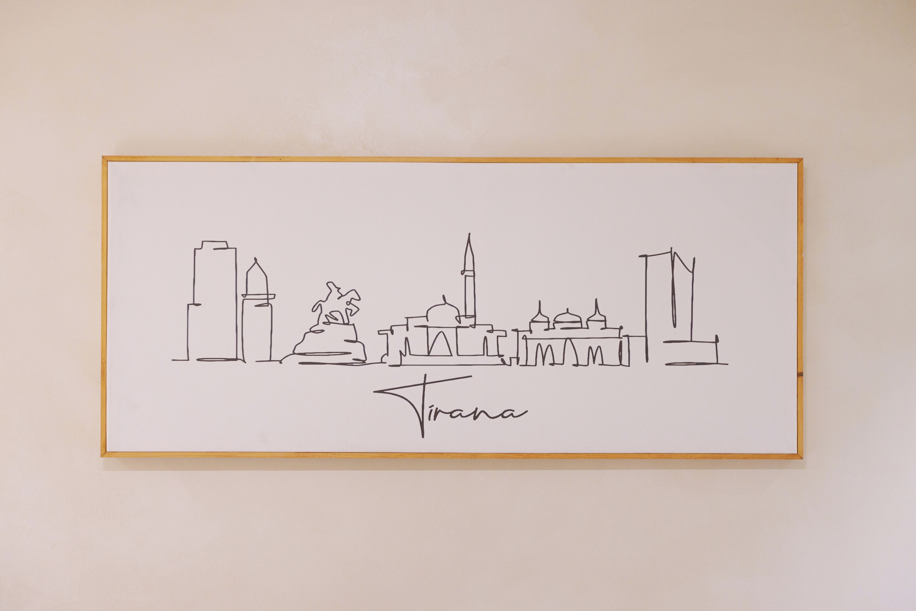 Een lijntekening van een stadsgezicht, met de naam 'Tirana' onderaan.