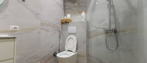A modern bathroom with a toilet, a shower, and a marble wall.