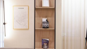 Een hoge houten boekenkast met het woord 'dream' bovenaan, een inlijsting kaart van Tirana, en een boek getiteld 'Tirana & de Balkan'.