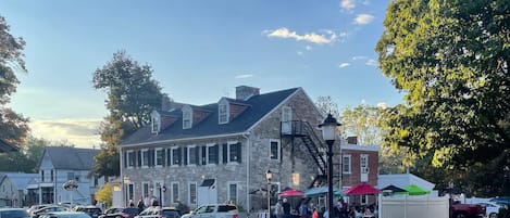 A historic stone building with a prominent staircase and a row of parked cars in front.