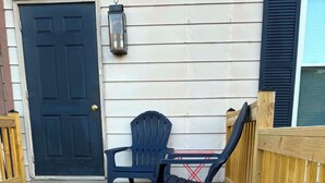 A wooden deck with a black door, a black Adirondack chair, and a small table. - Cozy 1-bedroom apartment in tranquil Boalsburg 7 minutes from the stadium (Boalsburg)