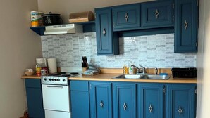 A kitchen with blue cabinets, a white stove, and a tiled backsplash. - Cozy 1-bedroom apartment in tranquil Boalsburg 7 minutes from the stadium (Boalsburg)