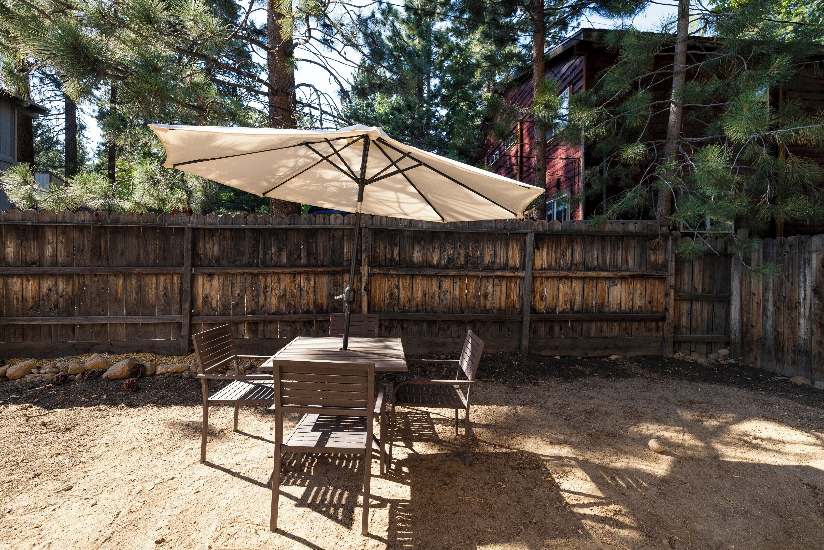 An outdoor patio with a table and chairs, a large umbrella, and a wooden fence.