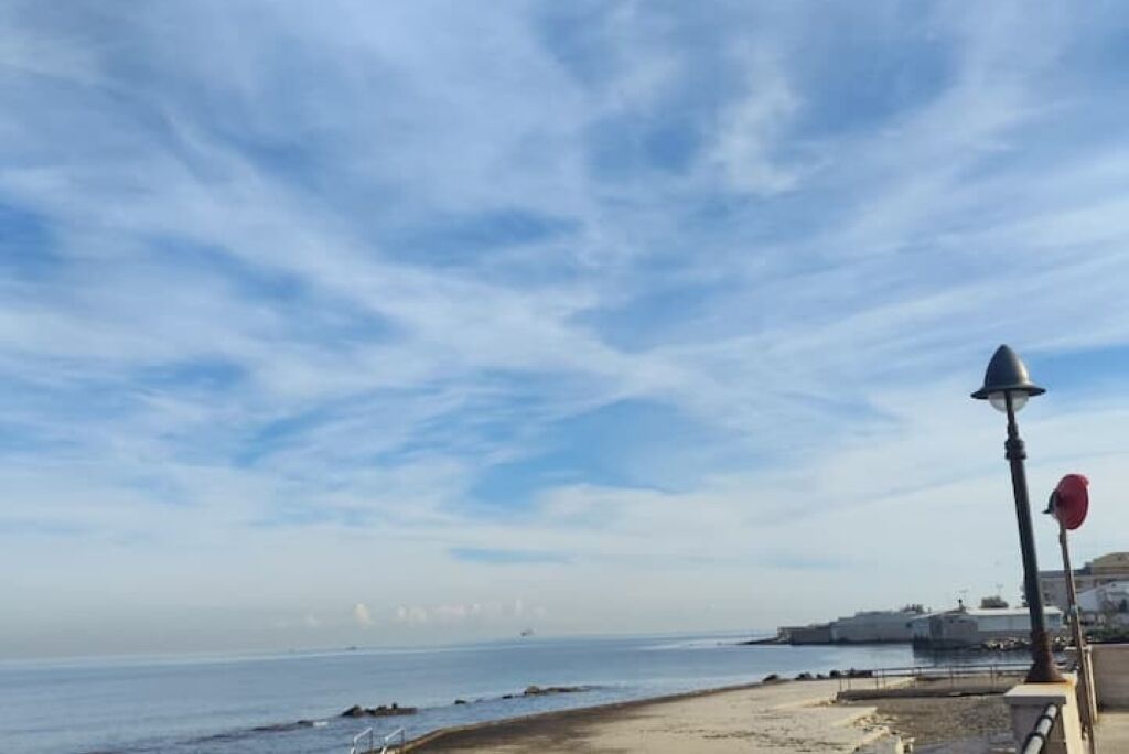 Vista costera con cielo despejado, playa de arena y un barco a lo lejos.