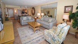 Ein Wohnzimmer mit Sofa, Sessel, Couchtisch und einem Essbereich mit Stühlen und Tisch.