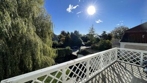 A balcony with a white lattice railing overlooking a residential area with houses and trees.