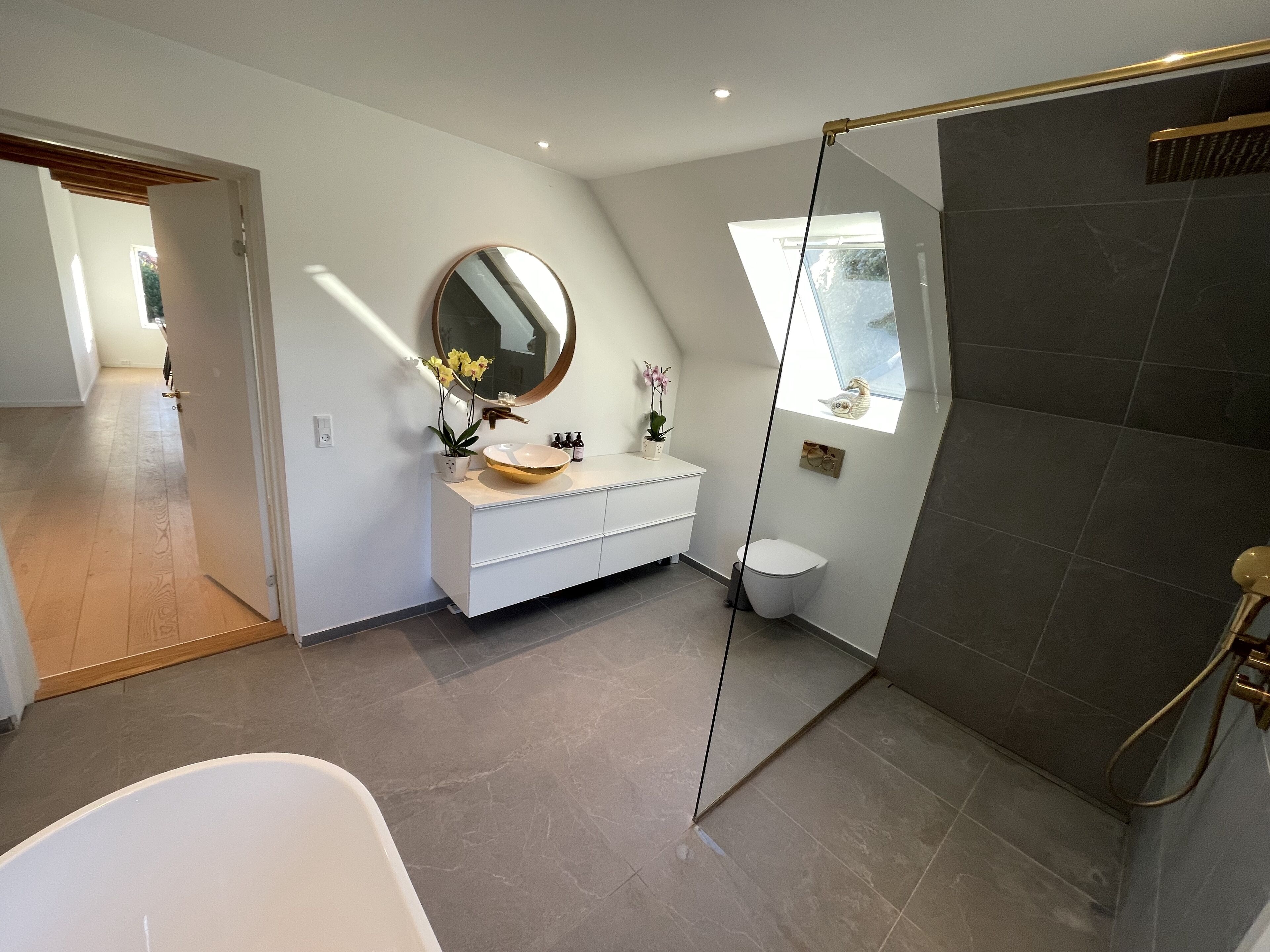 A modern bathroom with a freestanding bathtub, a vanity with a round mirror, and a shower area with a glass door.