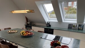 A modern kitchen with a central island, a dining area, and a view through a skylight.
