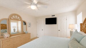 A bedroom with a bed, dresser, television, and ceiling fan. - Three Bedroom Two Bath Beachfront Condo (South Padre Island)