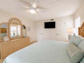 A bedroom with a bed, dresser, television, and ceiling fan. - Three Bedroom Two Bath Beachfront Condo (South Padre Island)