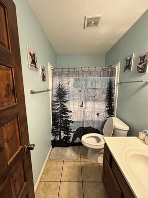 A bathroom with a shower curtain depicting birds and trees, a toilet, a sink, and wooden doors. -
#10 2-bedroom cottage in Salt Springs Under New Manage. Ice machine on site. (Salt Springs)