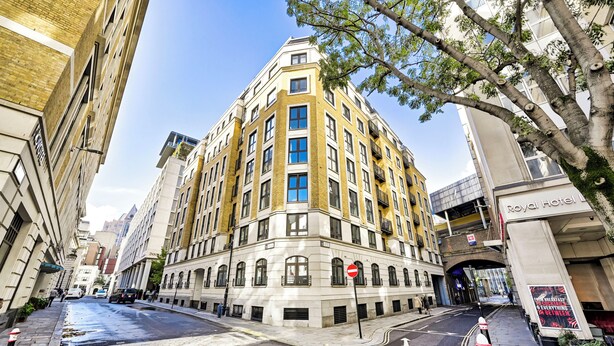 A corner building with a prominent Royal Hotel sign, a pedestrian crossing, and a tree in the foreground. - Luxury One-Bedroom by Tower of London • Prime Location (London)