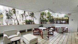 Ein geräumiger Balkon mit einer weißen Couch, Holzstühlen und einem kleinen Tisch.