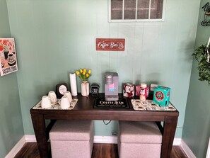 Ein Kaffee-Bereich mit einer Keurig-Maschine, Kaffeetassen, einer Tasse sowie verschiedenen Kaffeeprodukten und einem Schild mit der Aufschrift 'Coffee Bar'.