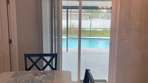 A room with a pool view, a dining table with chairs, and a sliding glass door leading outside. - Private Heated Screened Pool,  10 min to Beach, Coastal, Comfy, 3Bd/2B, Quiet
 (Sebastian)