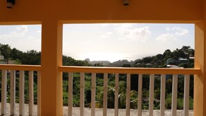 Ein Zimmer mit Balkon und Blick auf eine üppige Landschaft sowie ferne Hügel.