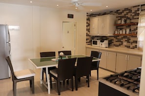 A compact kitchen with a dining table, chairs, a microwave, cabinets, and a gas stove. - 2-bedroom apartment in fabulous Harmony Hall Kingstown with AC and comfort (Kingstown)