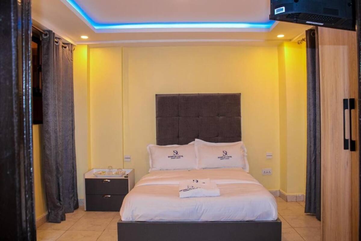 A hotel room with a bed, a nightstand, and a TV.
